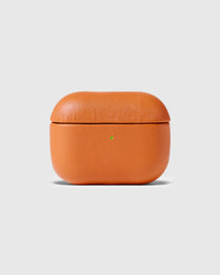 Orange genuine leather AirPods case closed with the green status light visible