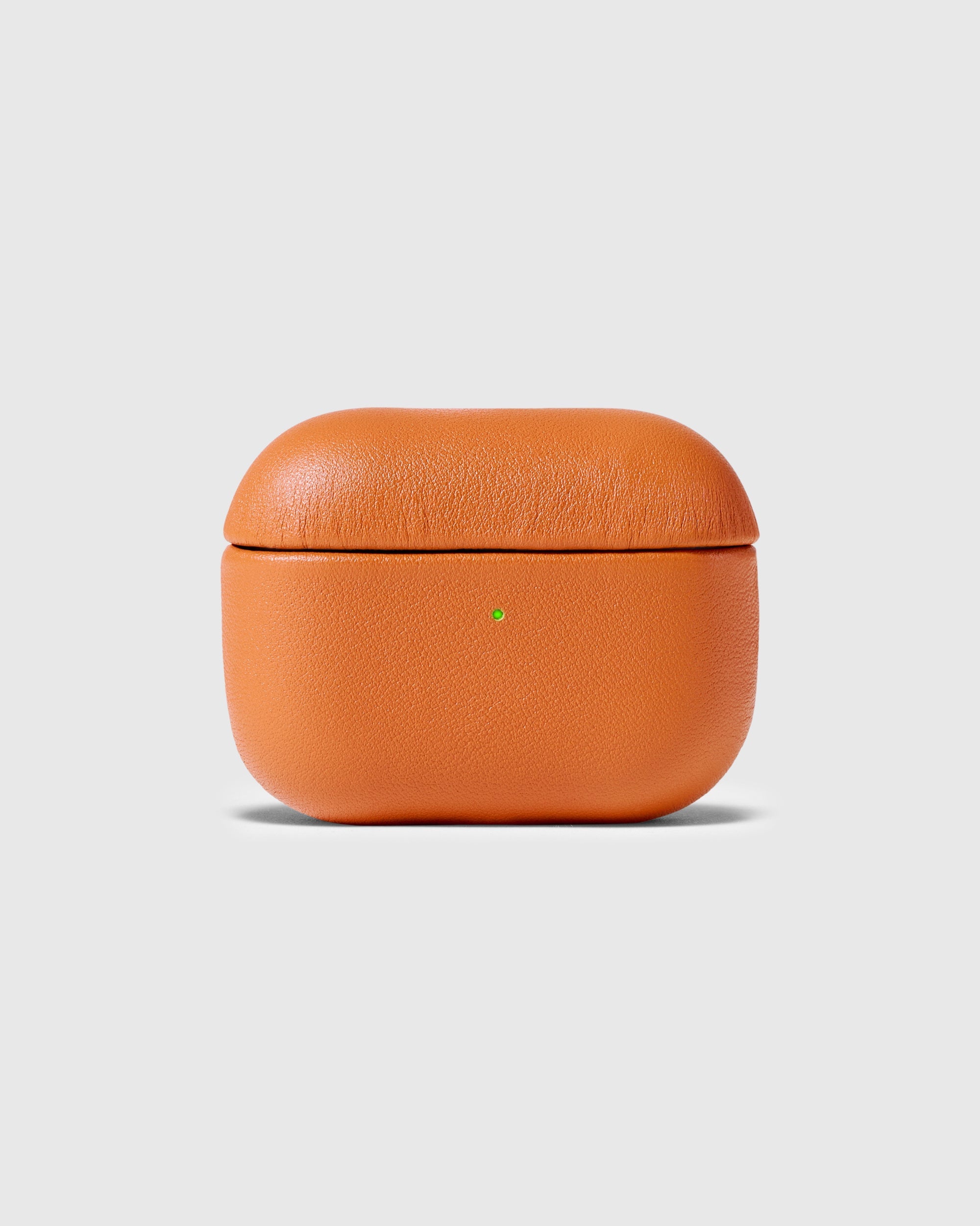 Orange genuine leather AirPods case closed with the green status light visible