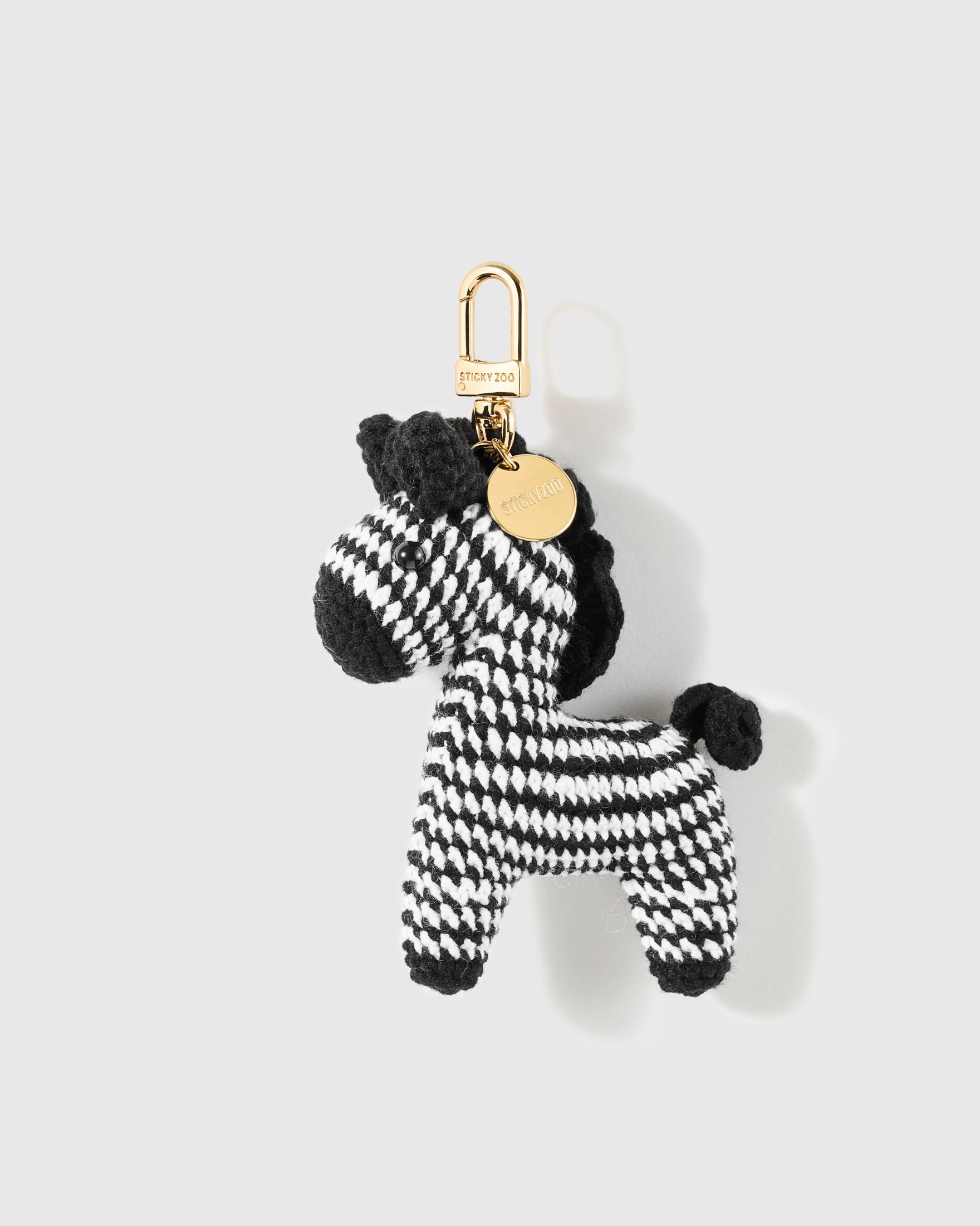 Monochrome Zebra Crochet Charm with alternating crochet stripes shape the long muzzle, upright ears, mane and four legs on a light background