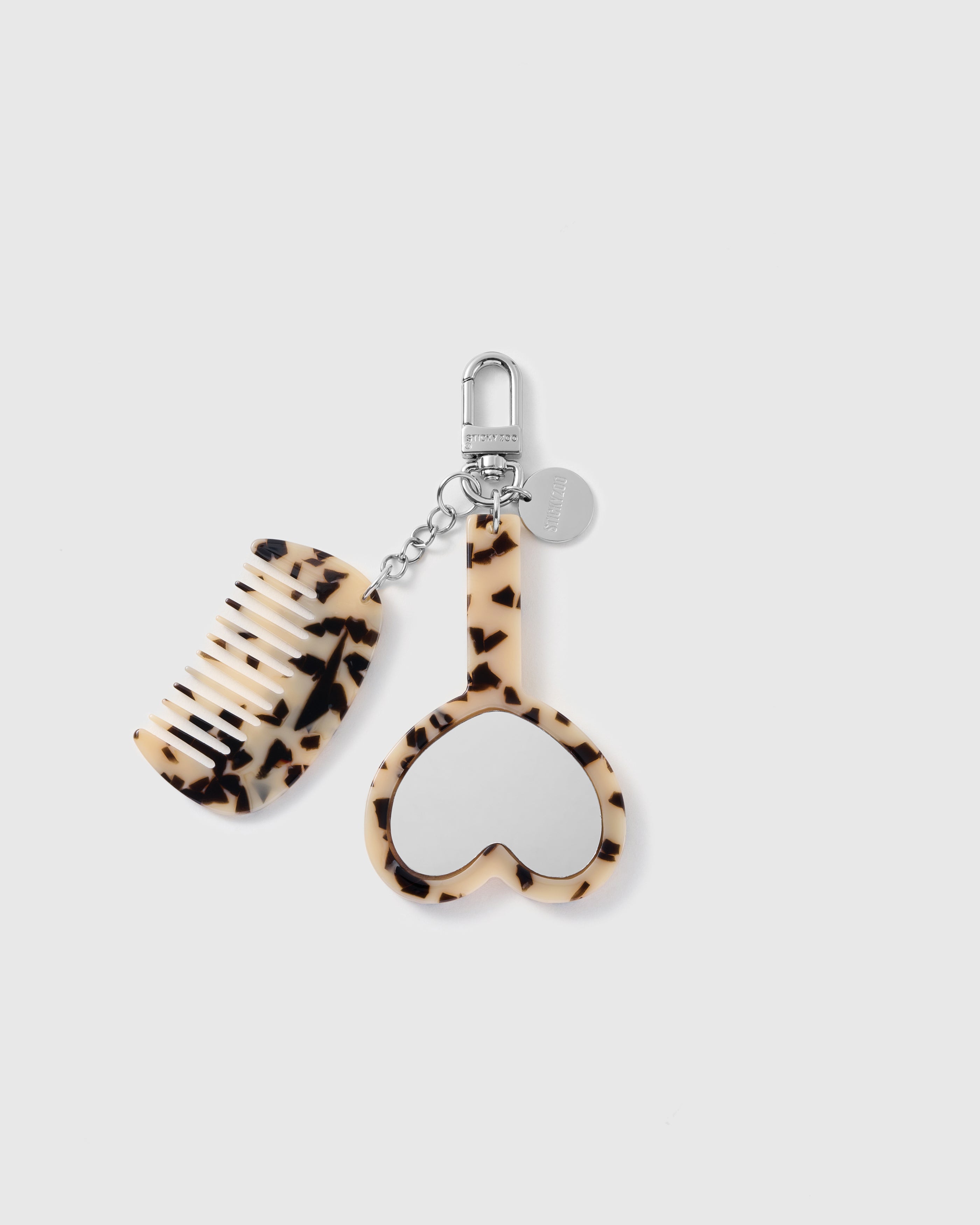 STICKYZOO cream tortoiseshell-pattern vanity stack charm with separate crescent comb, heart mirror, silver-tone clasp, chain and round tag.