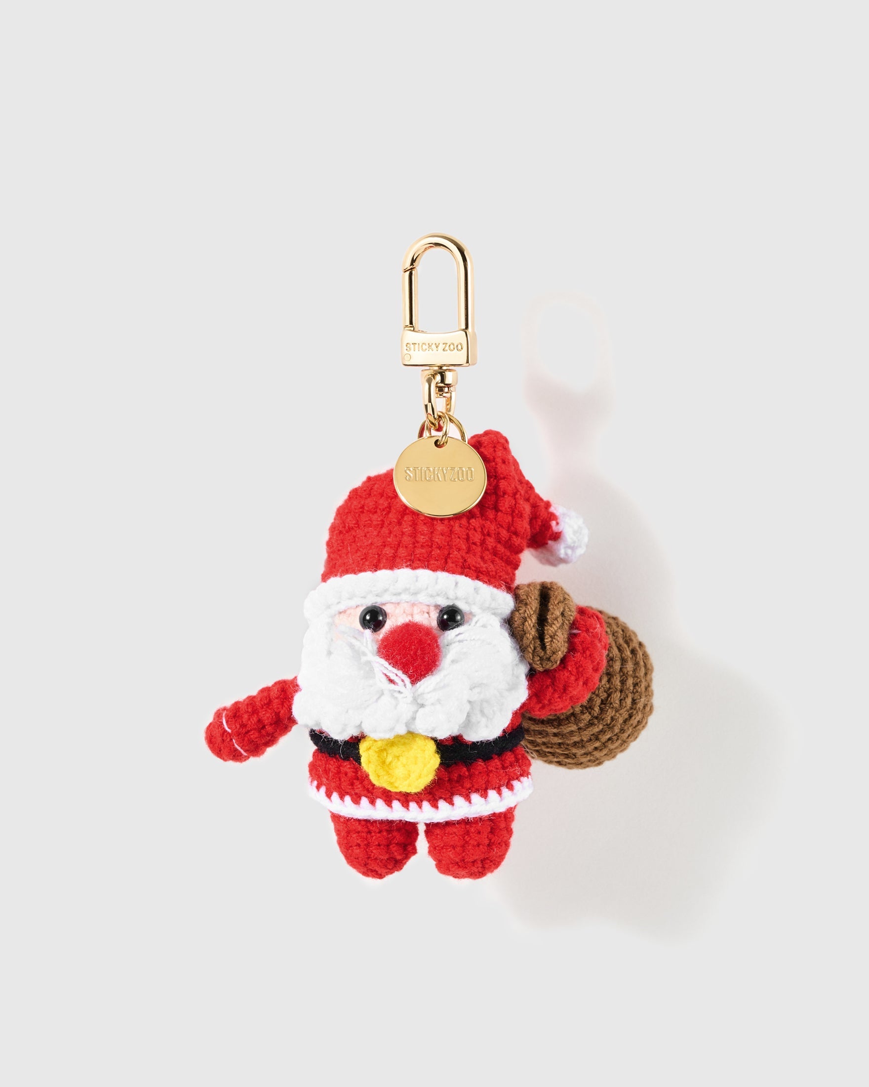 Santa Gift Sack Crochet Charm with the red-and-white crochet figure is finished with a brown sack and small gold-colour centre detail on a light background