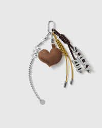Love Letter Heart Stack Charm with a stitched brown heart, letter motifs, silver-colour chain and dark braided cords on a light background