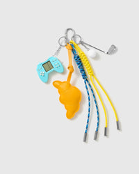 Croissant Golf Stack Charm with a croissant, golf motifs, blue game-controller piece and yellow-and-blue cords on a light background