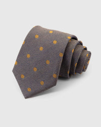 STICKYZOO Pewter Herringbone Dot Tie rolled on white, showing a pewter and charcoal herringbone field punctuated by small mustard-gold dots across the front blade.