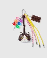 Tuxedo Cat Chocolate Stack Charm with a tuxedo-cat face, chocolate bar, number blocks and yellow-and-pink cords on a light background