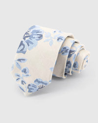 STICKYZOO Ivory Porcelain Bloom Tie rolled on white, showing an ivory ground with powder-blue and indigo blooms in a porcelain-inspired palette across the front blade.