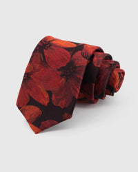STICKYZOO Oxblood Scarlet Bloom Tie rolled on white, showing an oxblood ground carrying vivid scarlet botanical blooms and dark leaves across the front blade.