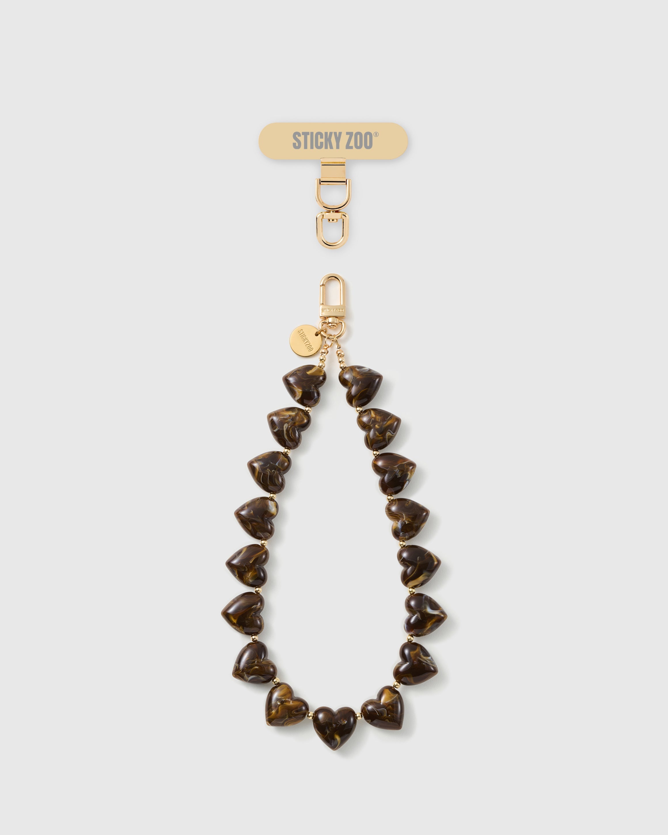 STICKYZOO Tortoiseshell Heart phone strap: full strand of amber-and-cocoa marbled heart beads with gold-tone hook, engraved disc and strap card.