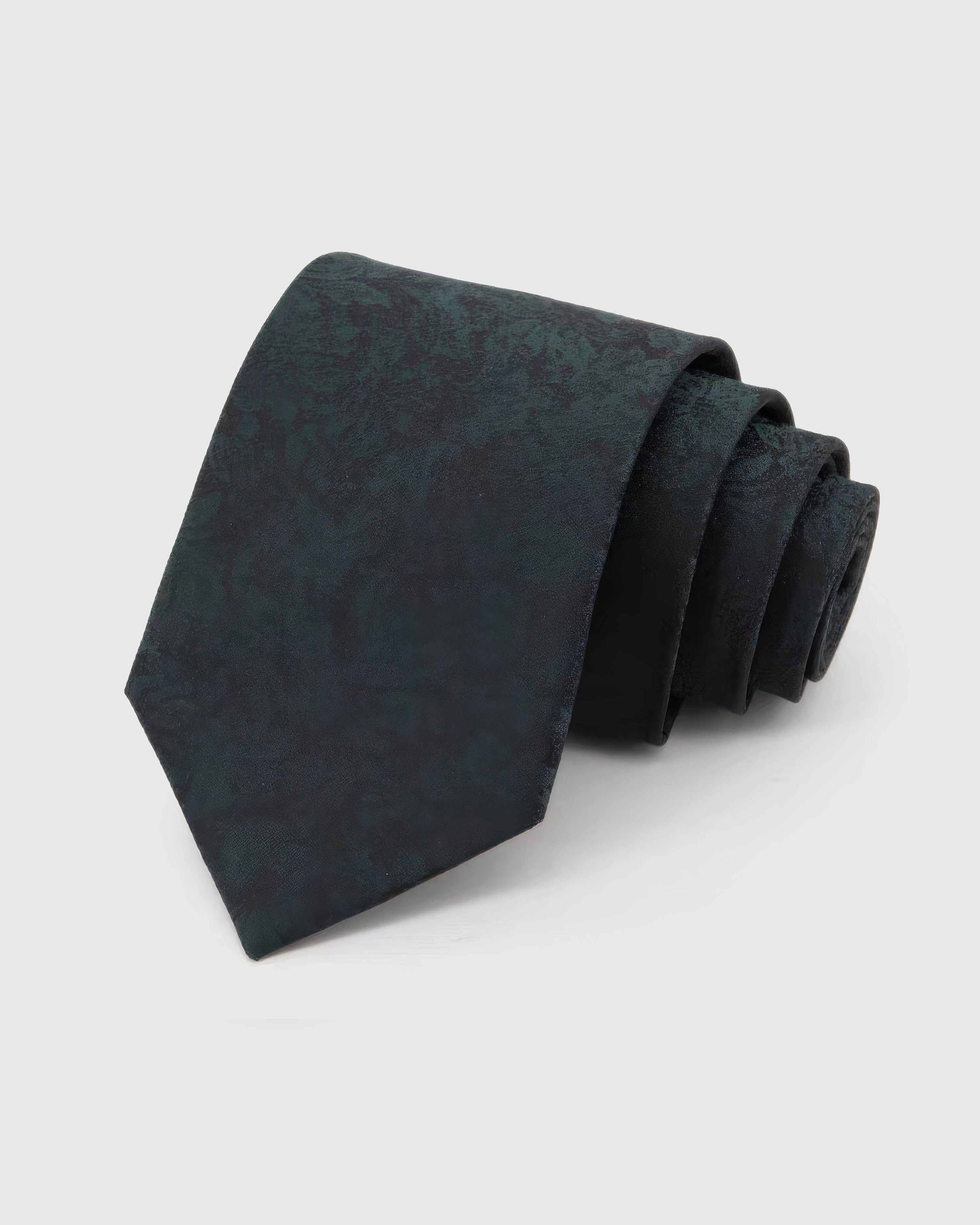 STICKYZOO Forest Shadow Floral Tie rolled on white, showing a low-contrast forest-teal field of shadowed florals and abstract foliage across the front blade.