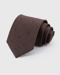 STICKYZOO Espresso Sapphire Paisley Tie rolled on white, showing a textured espresso ground with a compact sapphire-blue paisley repeat across the front blade.