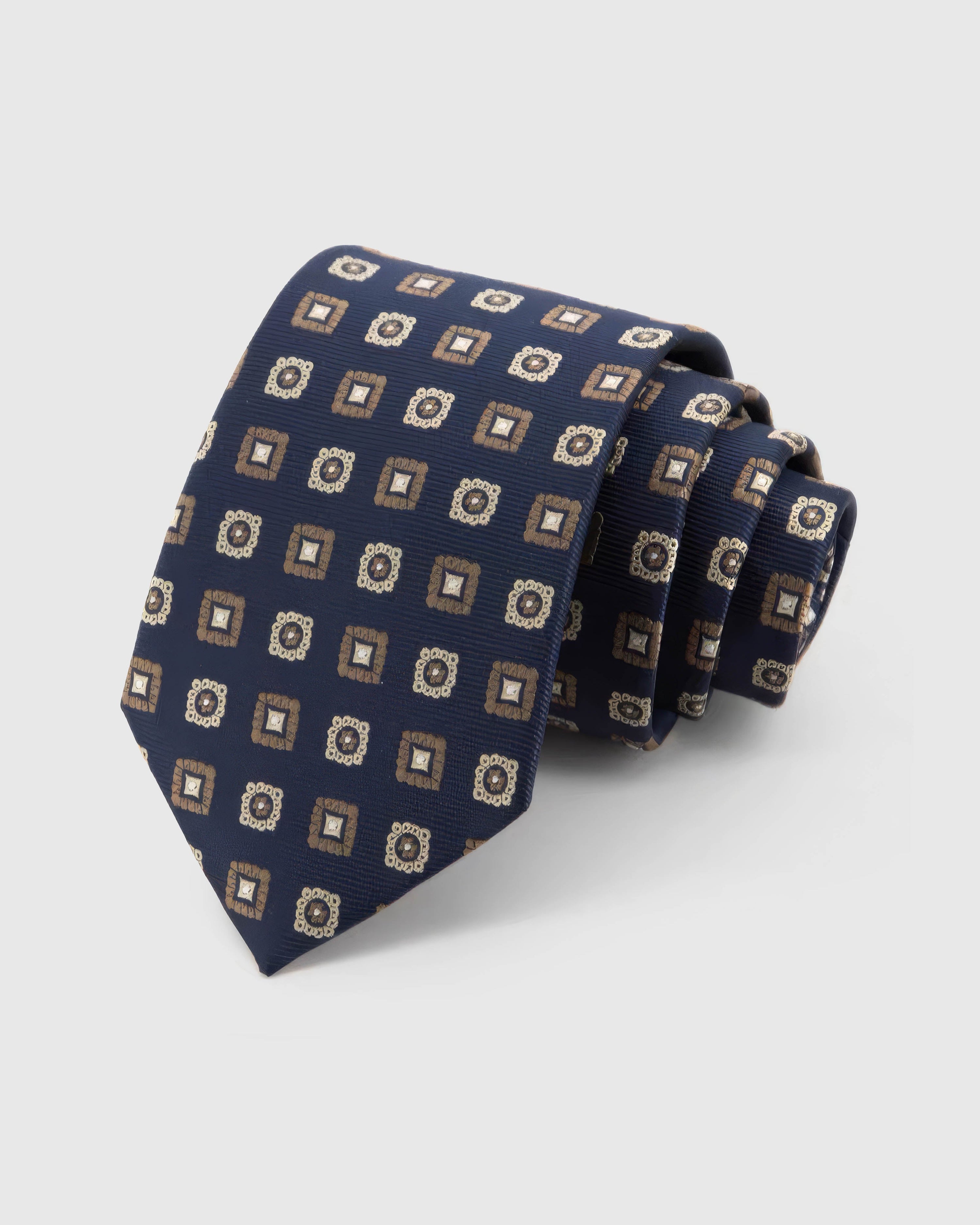 STICKYZOO Navy Medallion Tile Tie rolled on white, showing alternating tiles and rosette medallions across 100% mulberry silk in navy blue