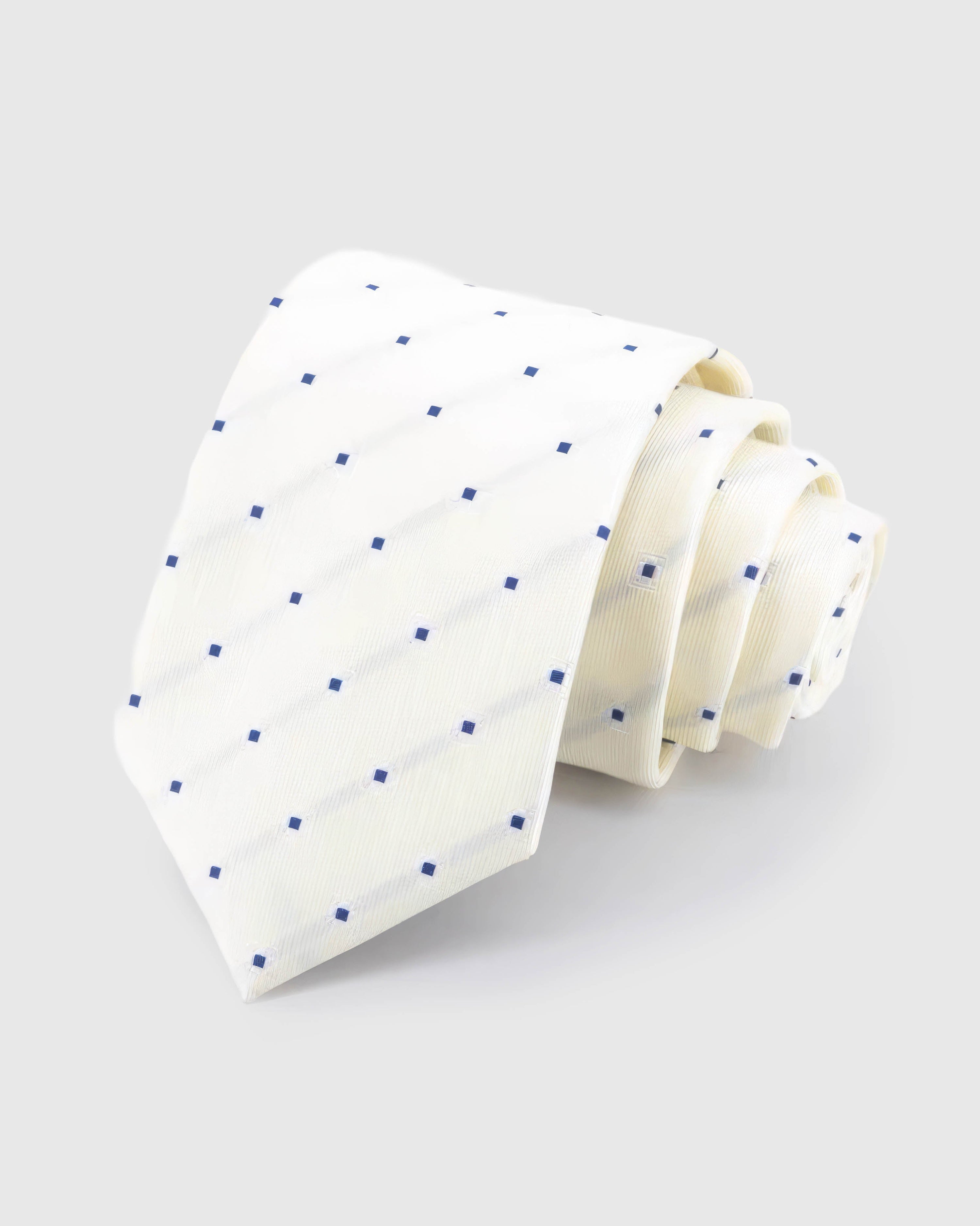 STICKYZOO Ivory Navy Square Tie in ivory silk, rolled to show ivory ground with spaced navy squares and tonal lines across the blade.