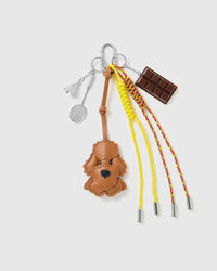 Poodle Chocolate Tennis Stack Charm with a brown poodle face, chocolate bar, tennis motif and yellow-and-red cords on a light background