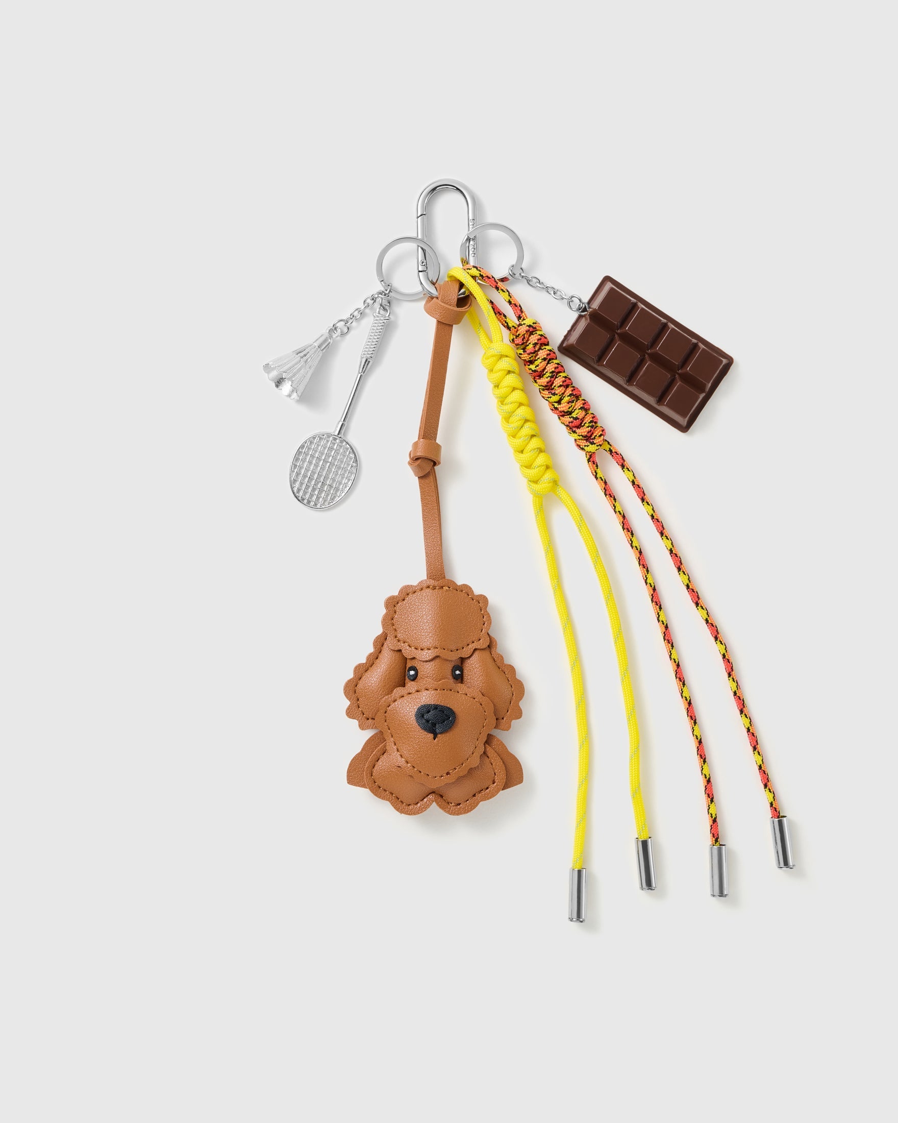 Poodle Chocolate Tennis Stack Charm with a brown poodle face, chocolate bar, tennis motif and yellow-and-red cords on a light background