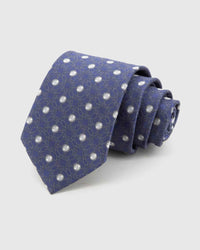 STICKYZOO Indigo Rosette Tie rolled on white, showing tonal rosette medallion lattice across 100% mulberry silk in indigo blue