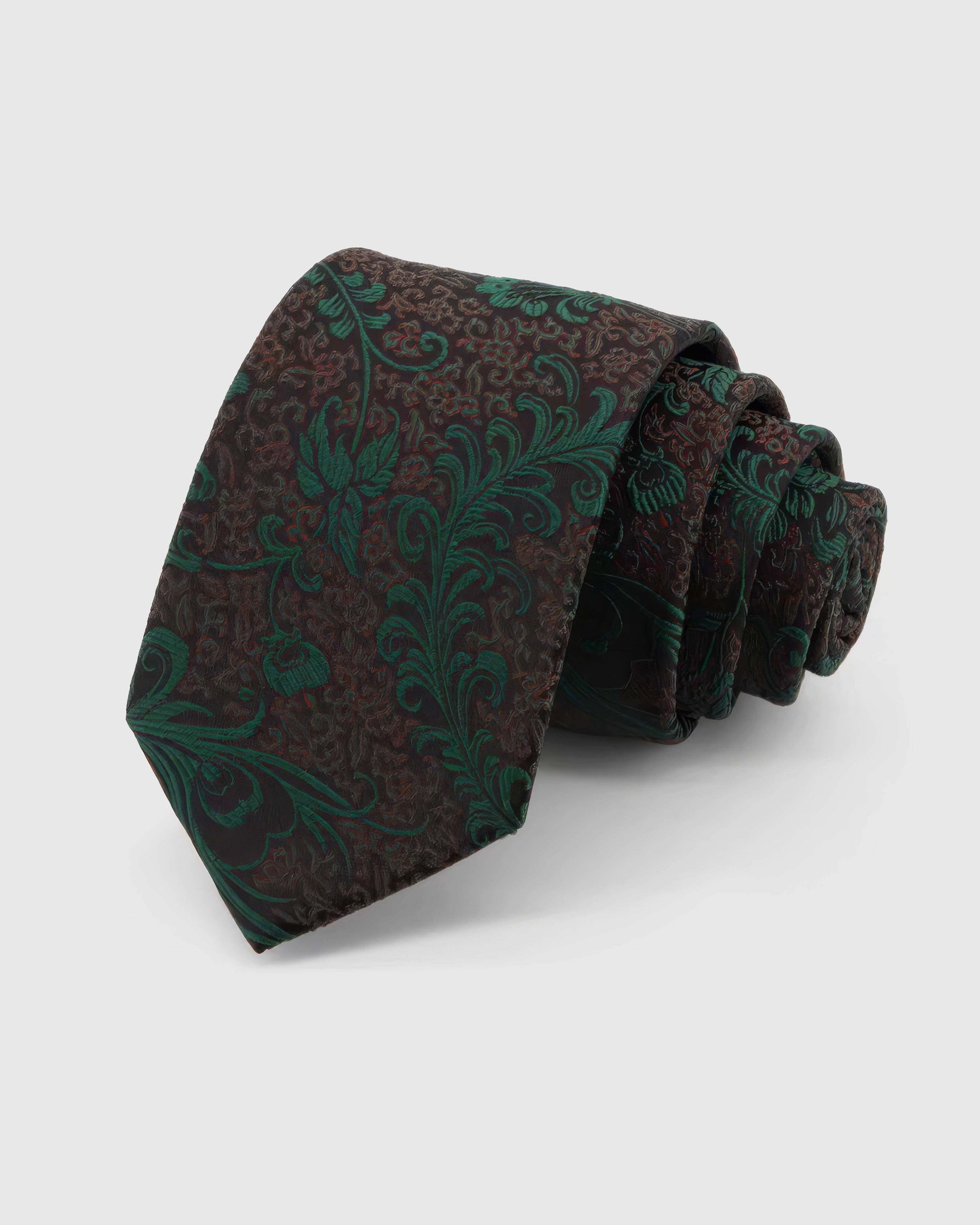 STICKYZOO Emerald Baroque Scroll Tie rolled on white, showing a dark brown-black ground with large emerald baroque scrolls and botanical flourishes across the front blade.
