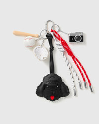 Midnight Poodle Baseball Stack Charm with a black poodle face, baseball motifs, miniature camera and red-and-black cords on a light background