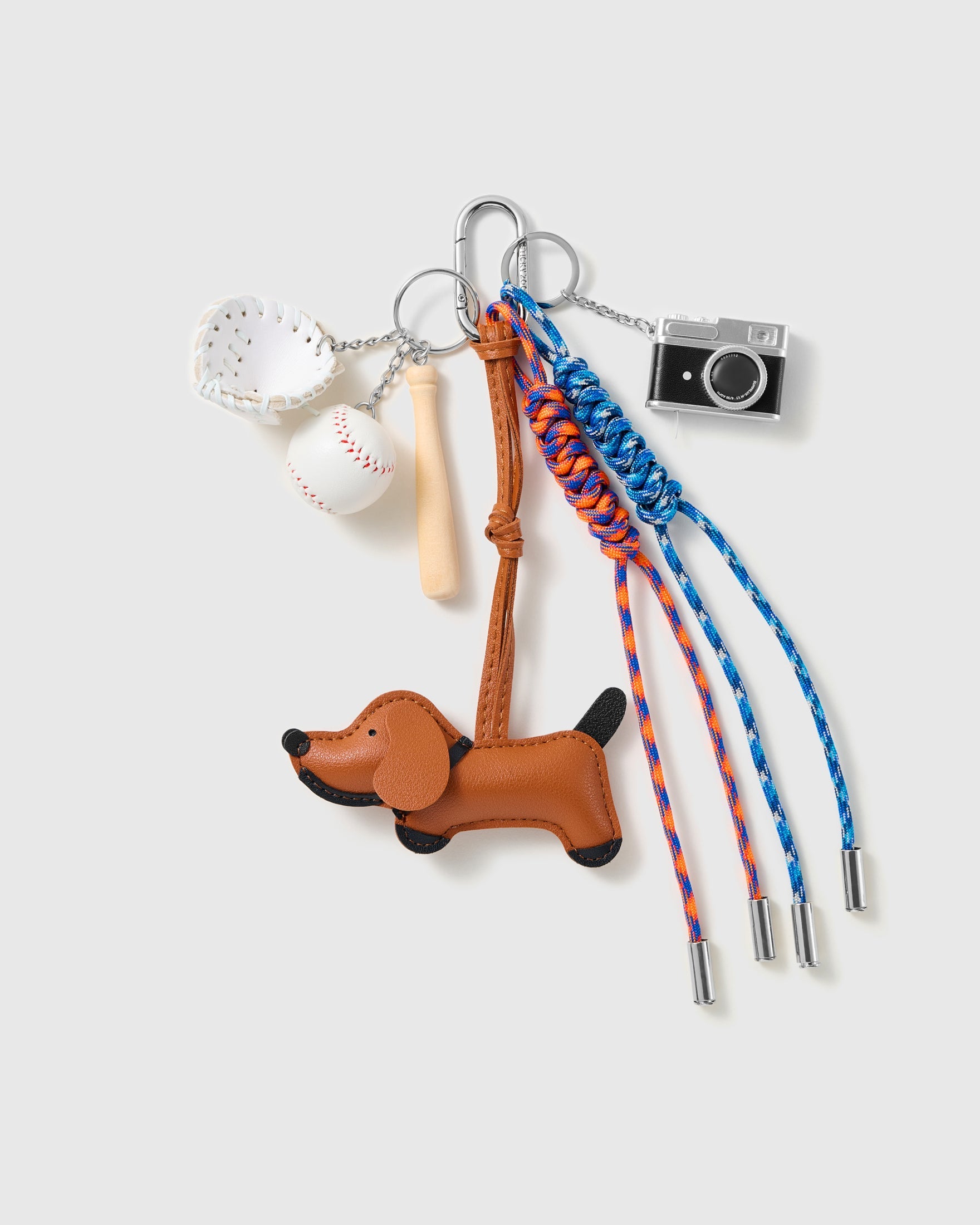 Dachshund Baseball Stack Charm with a brown dachshund, baseball motifs, miniature camera and blue-and-orange cords on a light background
