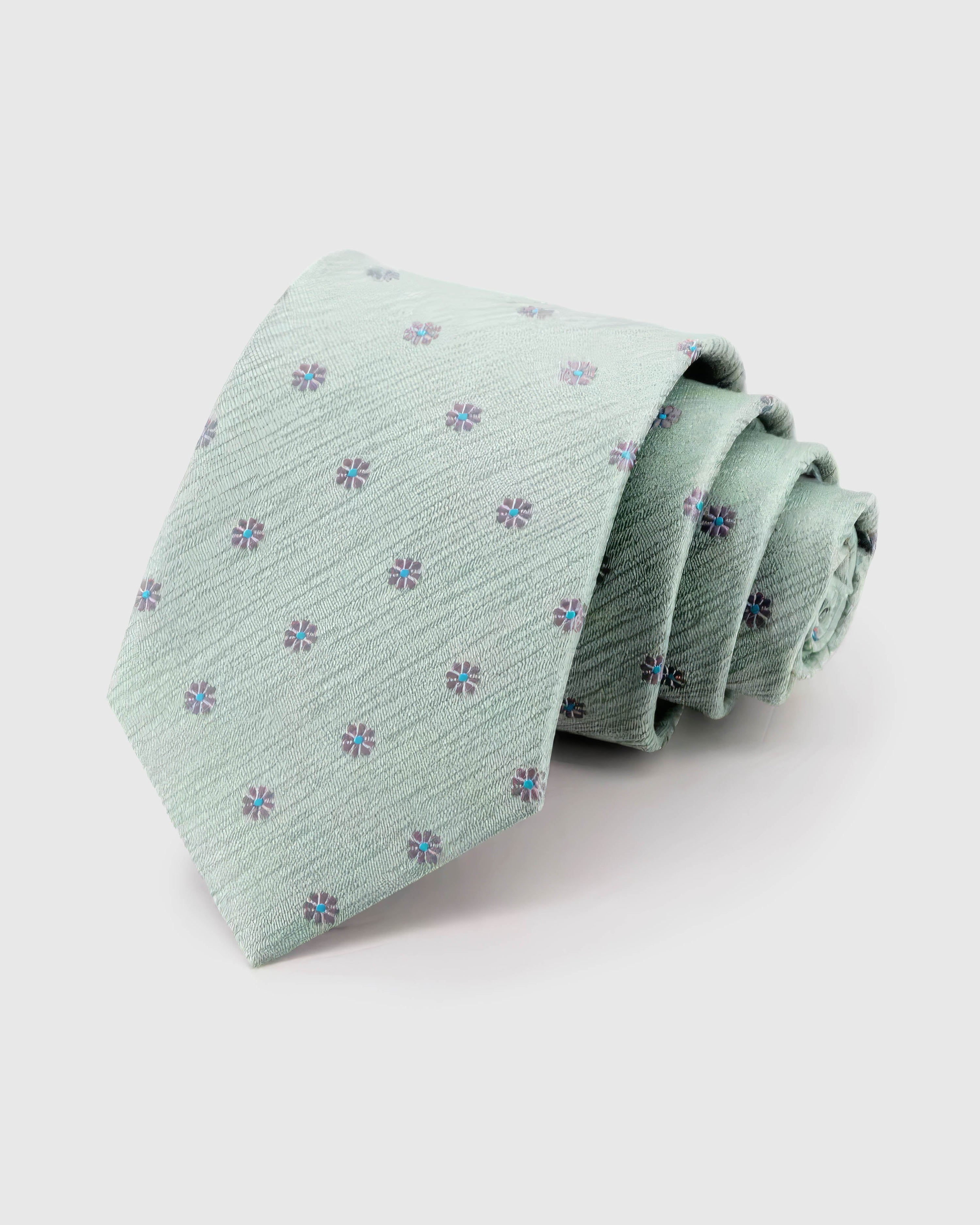 STICKYZOO Sage Blossom Tie rolled on white, showing mauve micro blossoms across 100% mulberry silk in sage mint