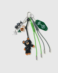 Black Pup Tennis Stack Charm with a black pup, tennis motifs, number blocks, stitched patches and green cords on a light background