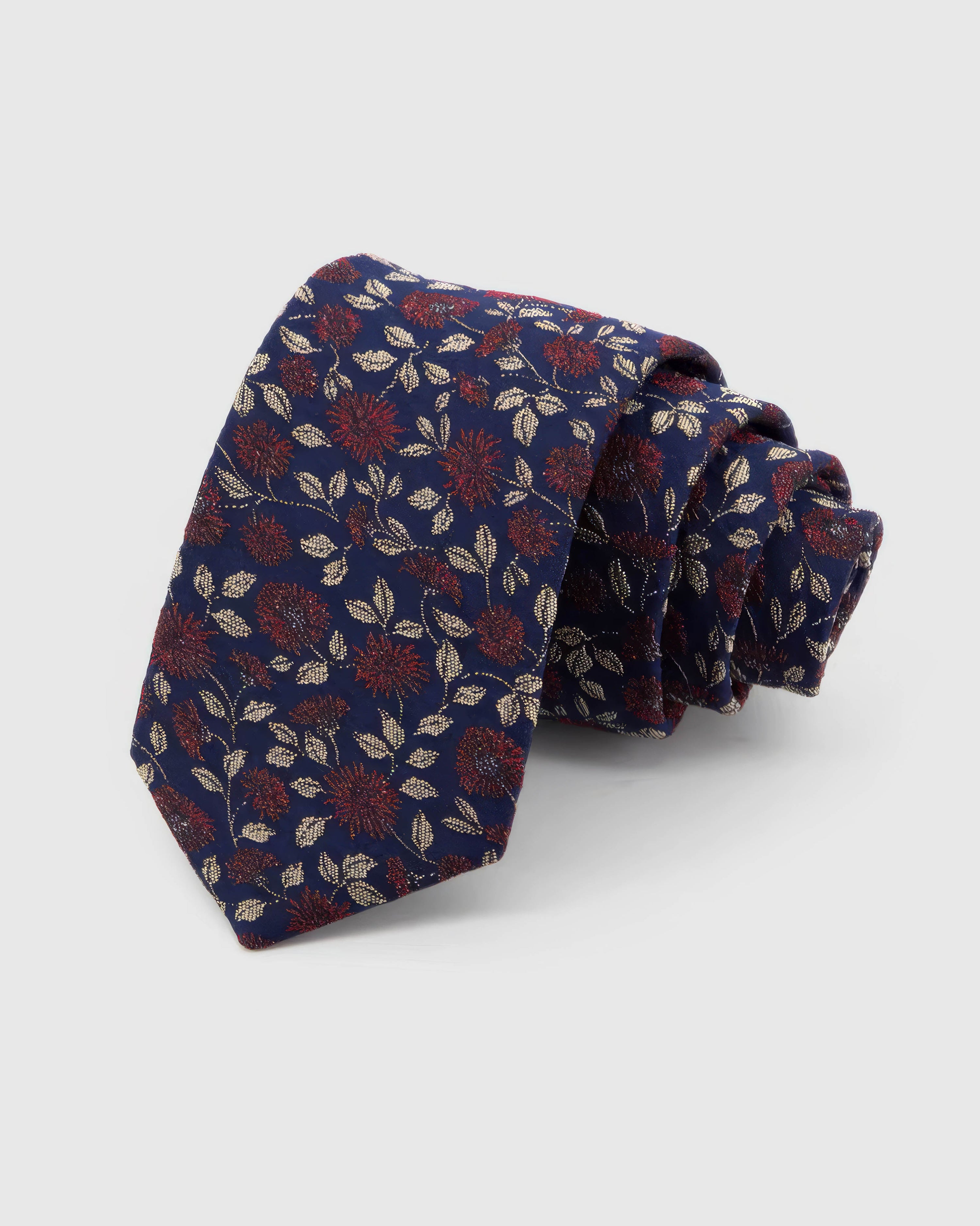STICKYZOO Midnight Crimson Meadow Tie rolled on white, showing a midnight ground scattered with crimson micro-blooms and small cream leaves across the front blade.