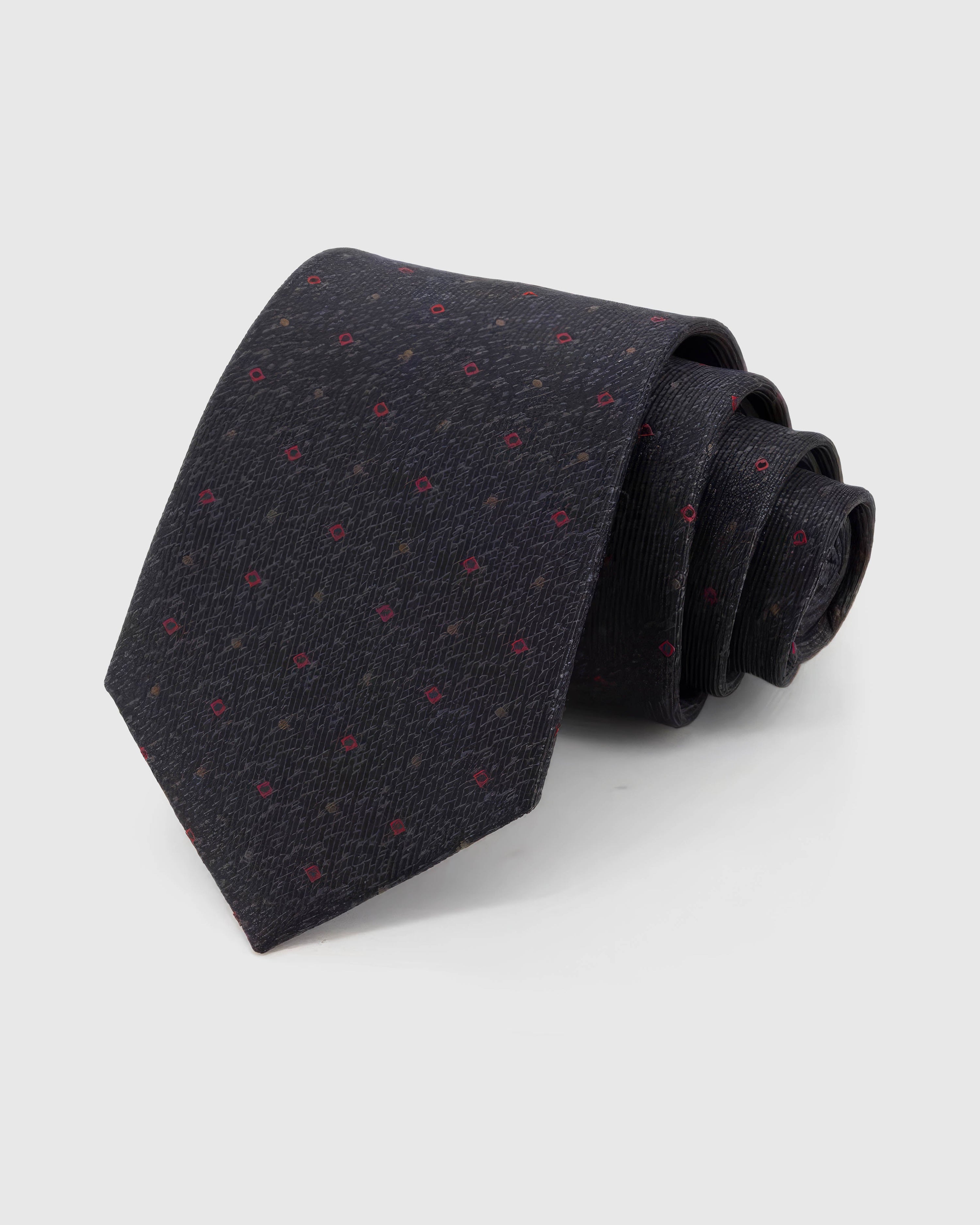 STICKYZOO Onyx Crimson Tile Tie rolled on white, showing crimson micro tiles and bronze dots across 100% mulberry silk in onyx black