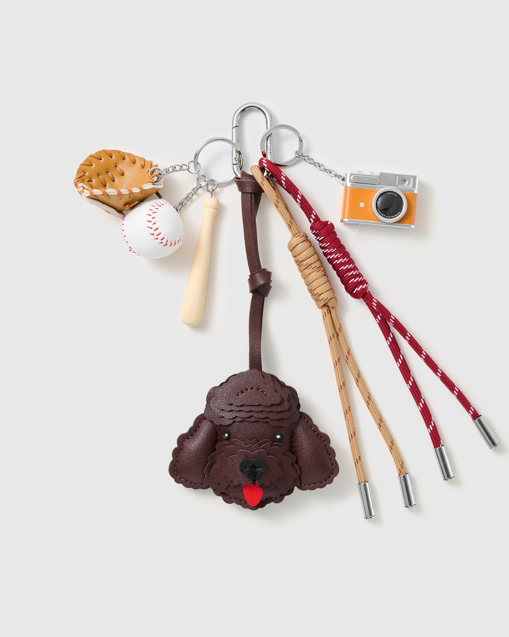 Espresso Poodle Baseball Stack Charm with an espresso-brown poodle face, baseball motifs, miniature camera and red-and-brown cords on a light background