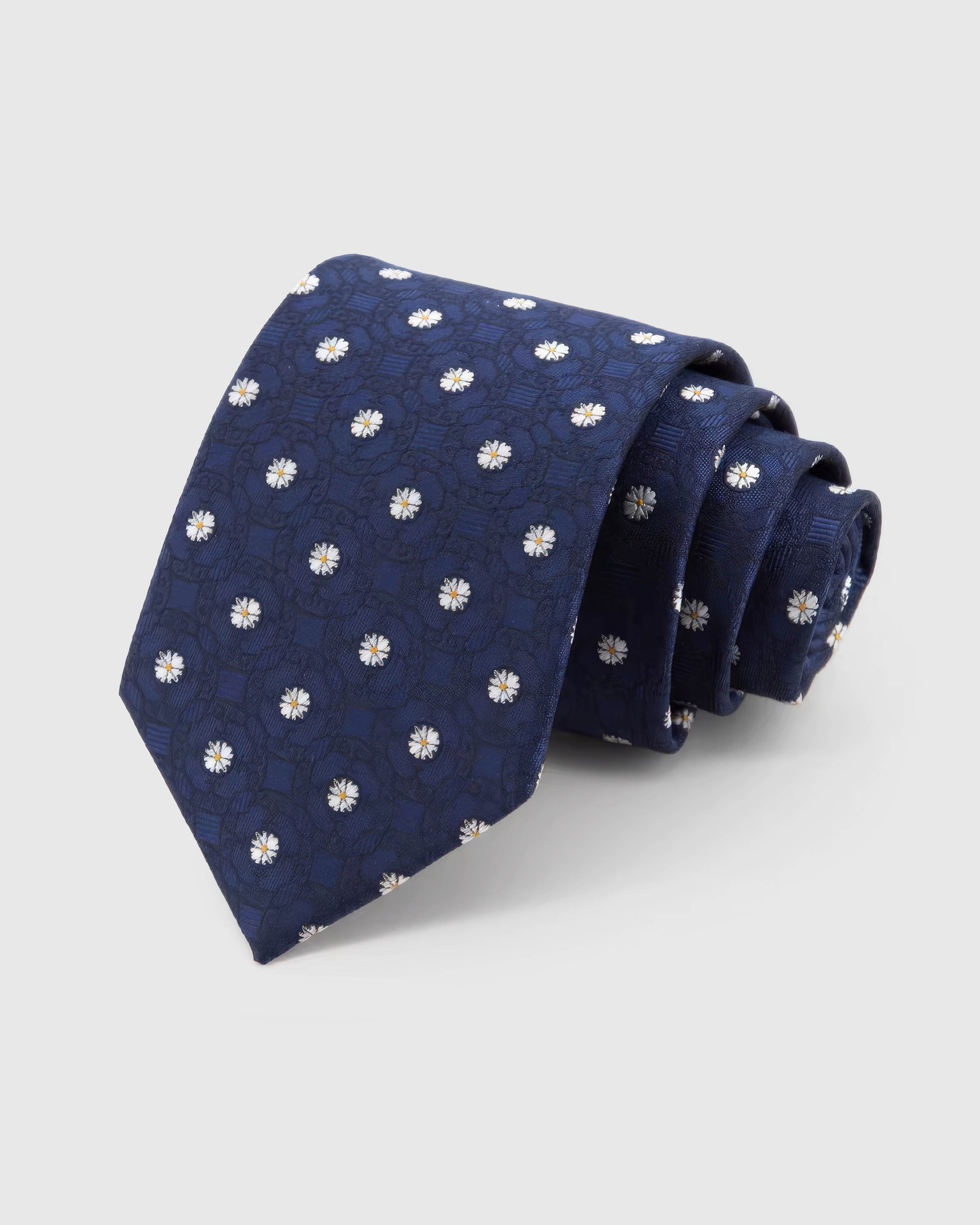 STICKYZOO Midnight Daisy Tie rolled on white, showing white daisies over tonal medallions across 100% mulberry silk in midnight navy