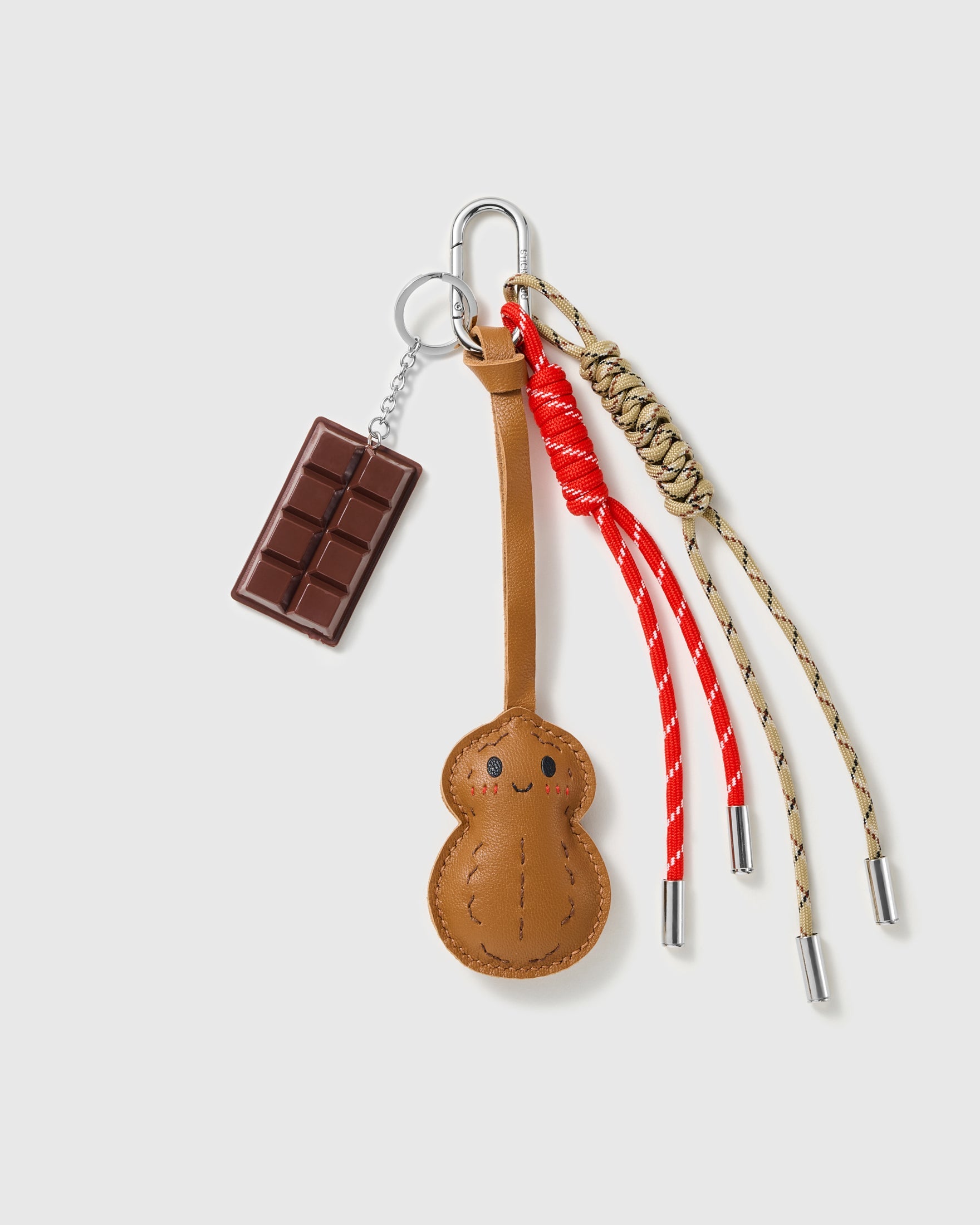 Chocolate Peanut Stack Charm with a chocolate bar, smiling peanut motif, bow detail and warm neutral cords on a light background