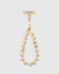 Marbled ivory heart bead phone strap laid straight, with a gold hook, an engraved gold disc, and a STICKYZOO phone-strap card at the top.