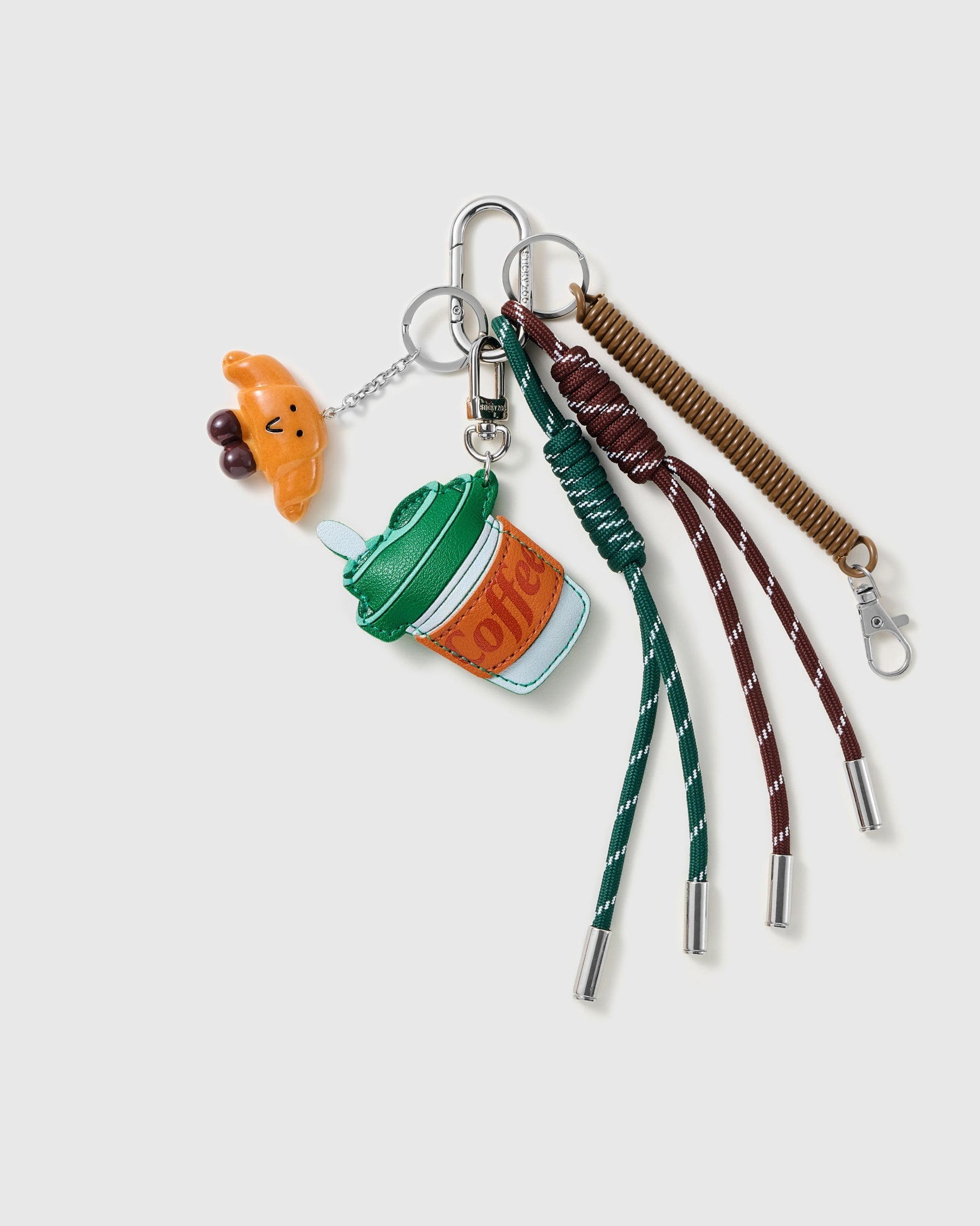 Coffee & Croissant Stack Charm with a takeaway coffee cup, croissant, bead detail and coffee-colour cords on a light background