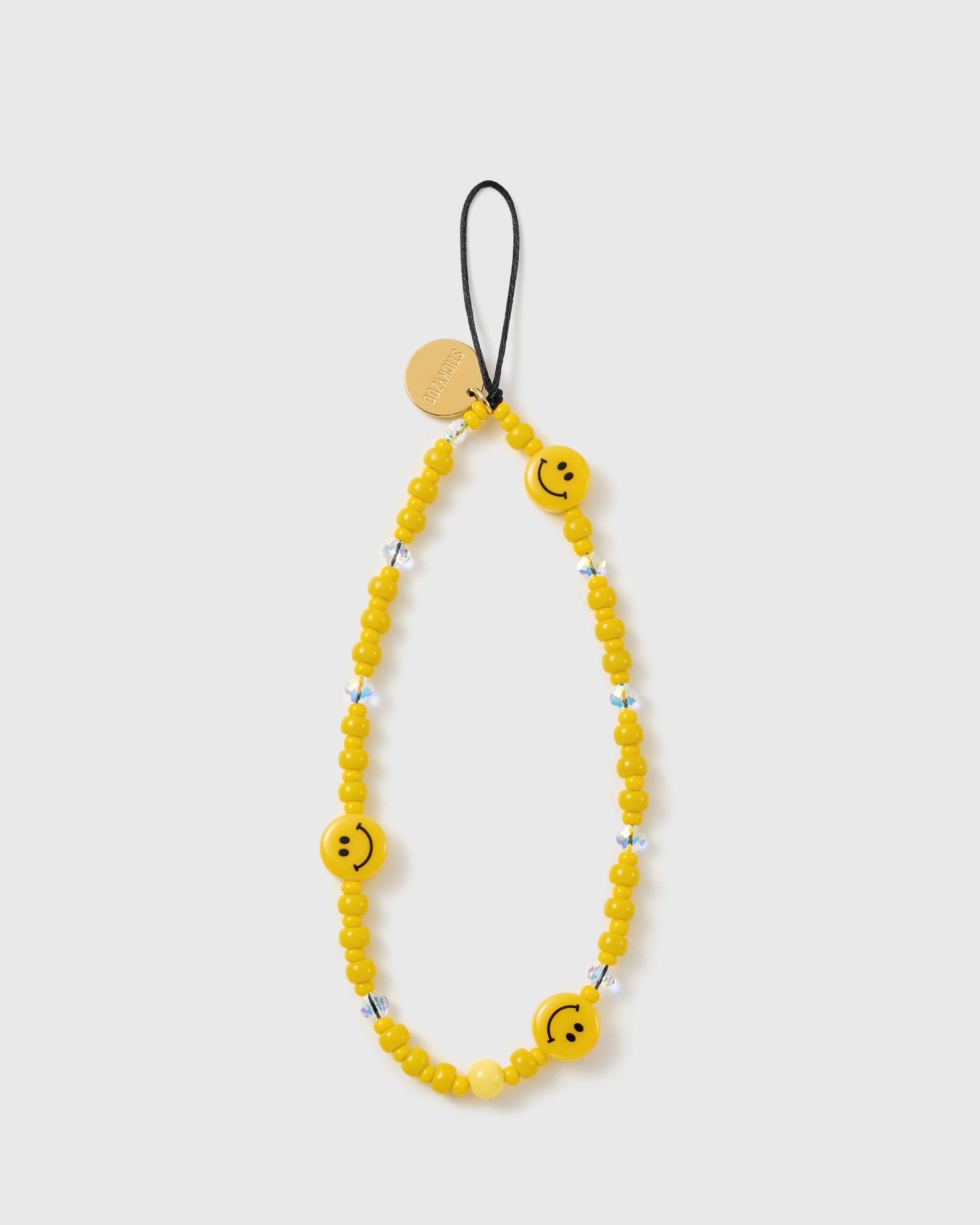 STICKYZOO Sunshine Smiley phone strap laid flat, a full loop of glossy yellow beads with three smiley-face beads, faceted clear accents and gold disc.