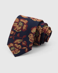 STICKYZOO Navy Gilded Bloom Tie rolled on white, showing a navy ground with large burgundy-red and gilded botanical blooms across the front blade.