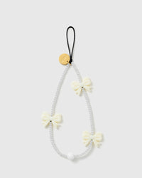 STICKYZOO Ivory Bow phone strap with white faux-pearl beads, three glossy ivory bows, a gold-tone disc and black cord loop.