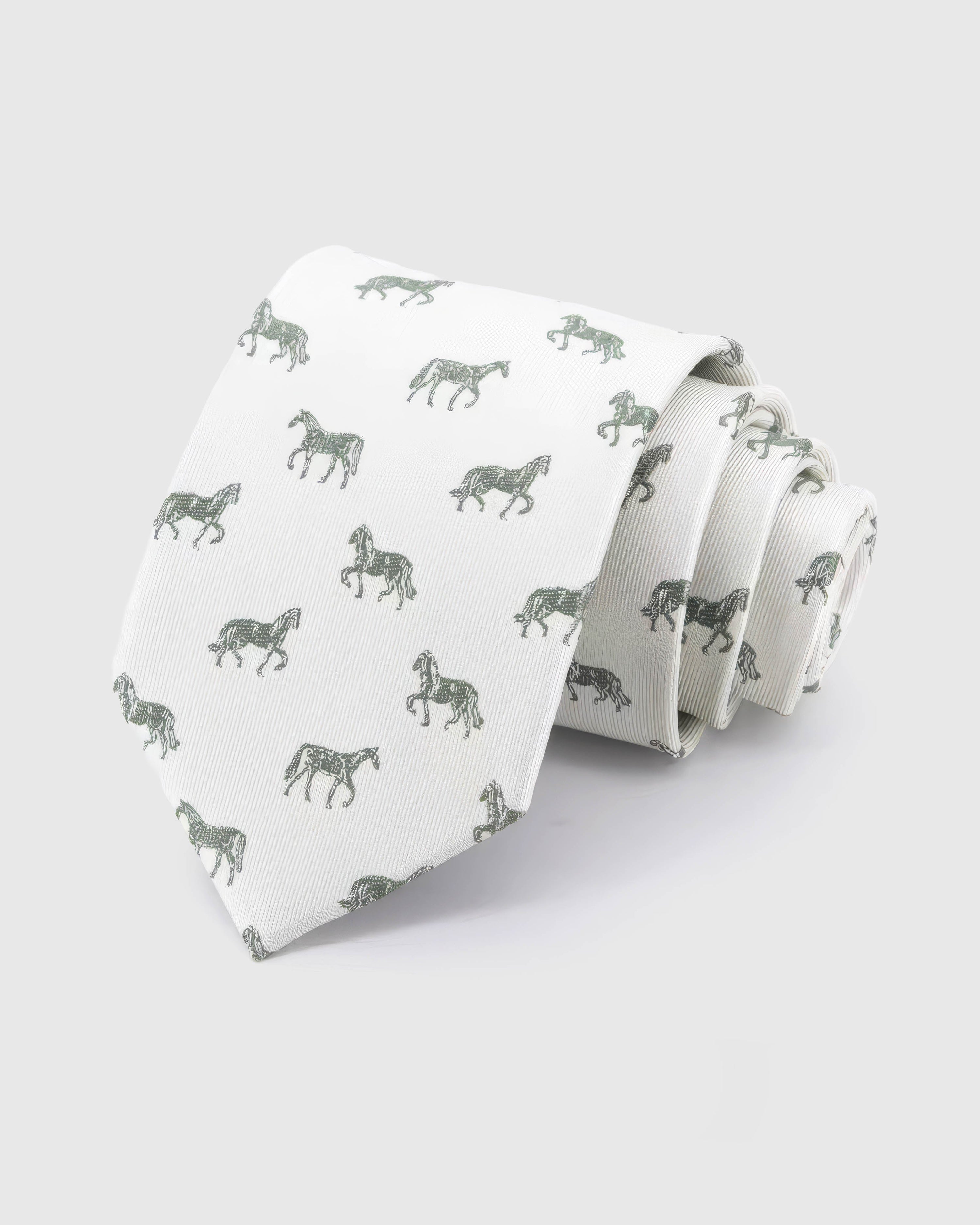 STICKYZOO Ivory Equestrian Tie in ivory silk, rolled to show ivory ground with sage and forest horse silhouettes across the blade.