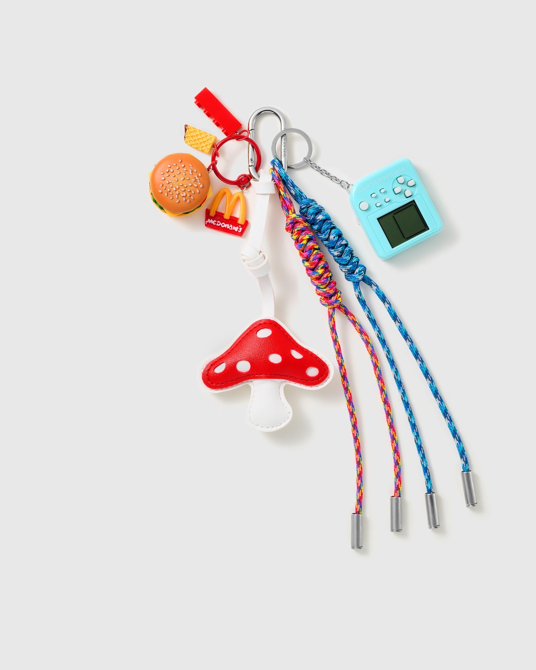 Burger Mushroom Arcade Stack Charm with a red mushroom, burger motif, blue handheld-game piece and blue-and-red cords on a light background