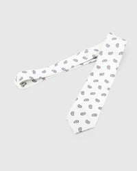 Ivory Tricolor Paisley Tie laid full length on white, showing an ivory ground with small navy-outline paisleys and crisp crimson centres from blade to tail.