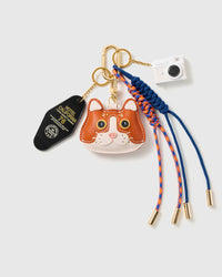 Camera Cat Stack Charm with a cat-face motif, miniature camera, stitched tag and blue-and-orange cords on a light background