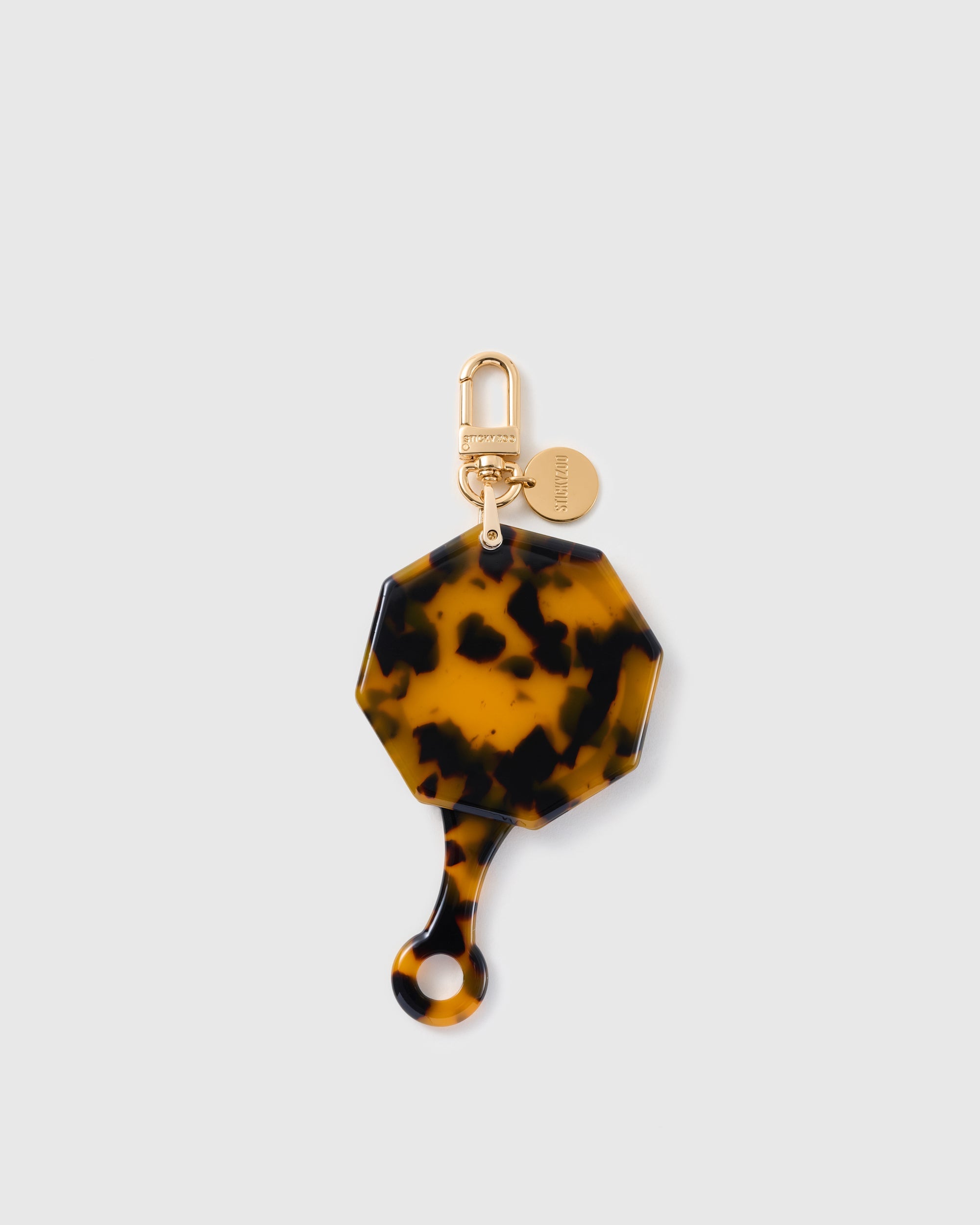STICKYZOO folding octagonal mirror charm in Brown with tortoiseshell-style surface, gold-tone linework and branded clasp.