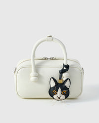 Tuxedo cat charm styled on a cream box bag, front — a small, specific piece that turns a simple bag into a personal one.