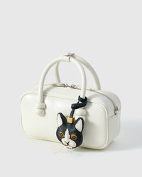 Tuxedo cat charm on a cream box bag, side angle — Real French leather, 3 days by hand.