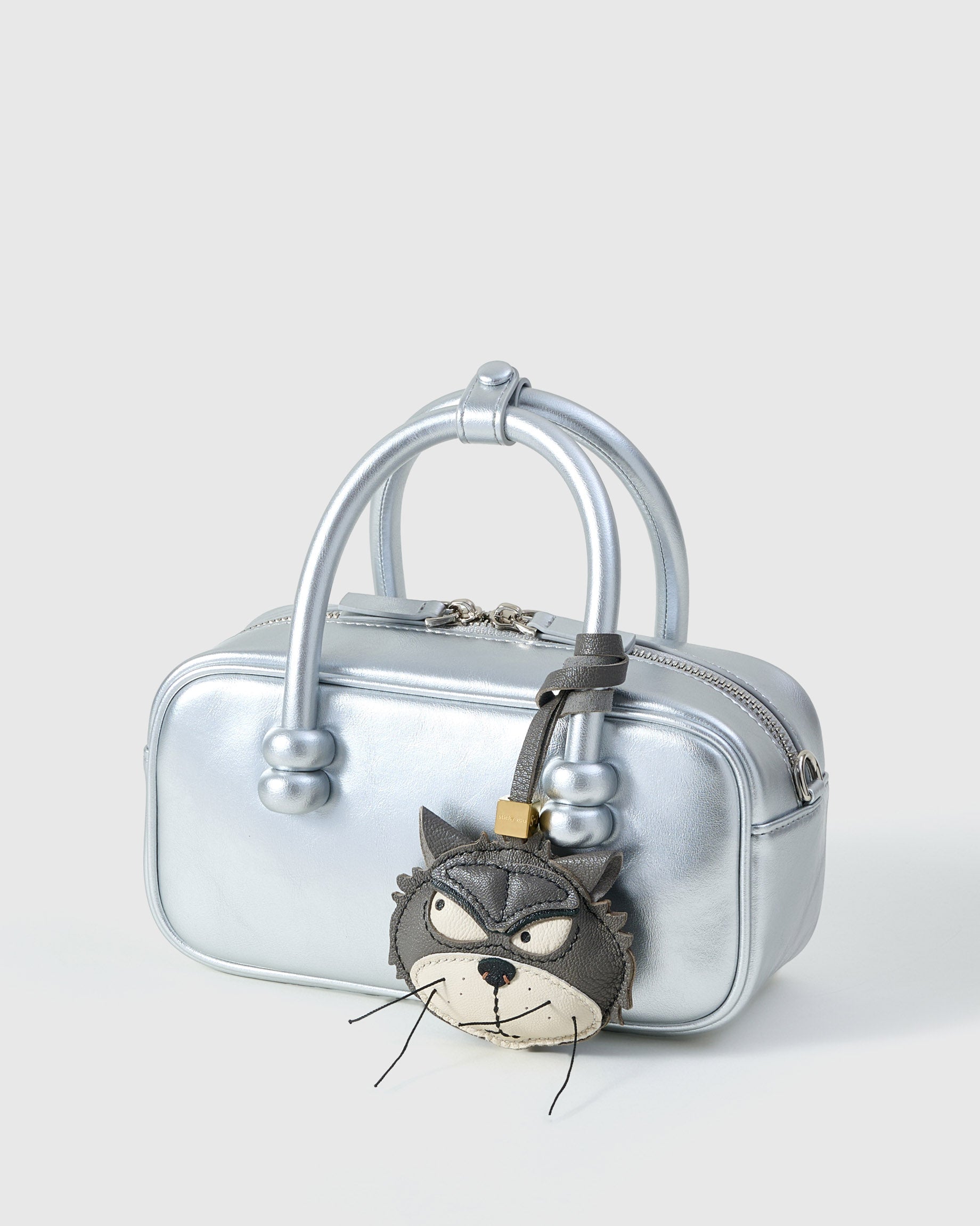 Grump cat charm on a metallic silver box bag, side angle — loved by thousands of cat people. Real French leather, 3 days by hand.