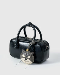 Grump cat charm on a glossy black box bag, side angle — rated 4.9★ by thousands of buyers. Real French Alran leather, 3 days by hand.
