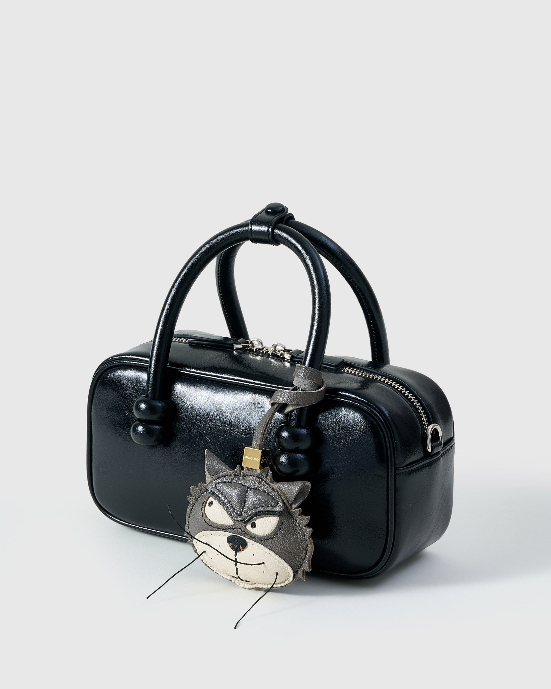 Grump cat charm on a glossy black box bag, side angle — rated 4.9★ by thousands of buyers. Real French Alran leather, 3 days by hand.