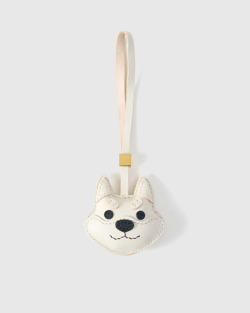 White Tokyo Shiba charm handmade from French Alran genuine goatskin and French suede — real full-grain leather from Tarn, since 1903. 3 days of hand-cutting, hand-stitching, hand-layering. Arrives in luxury gift packaging. Designed in Amsterdam.