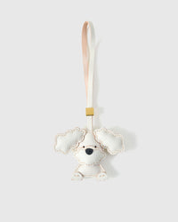 Handmade sitting Poodle Puppy leather bag charm by STICKYZOO — hand-cut, hand-stitched, hand-layered French Alran goatskin over 3 days in cream. Full-body design. Designed in Amsterdam.