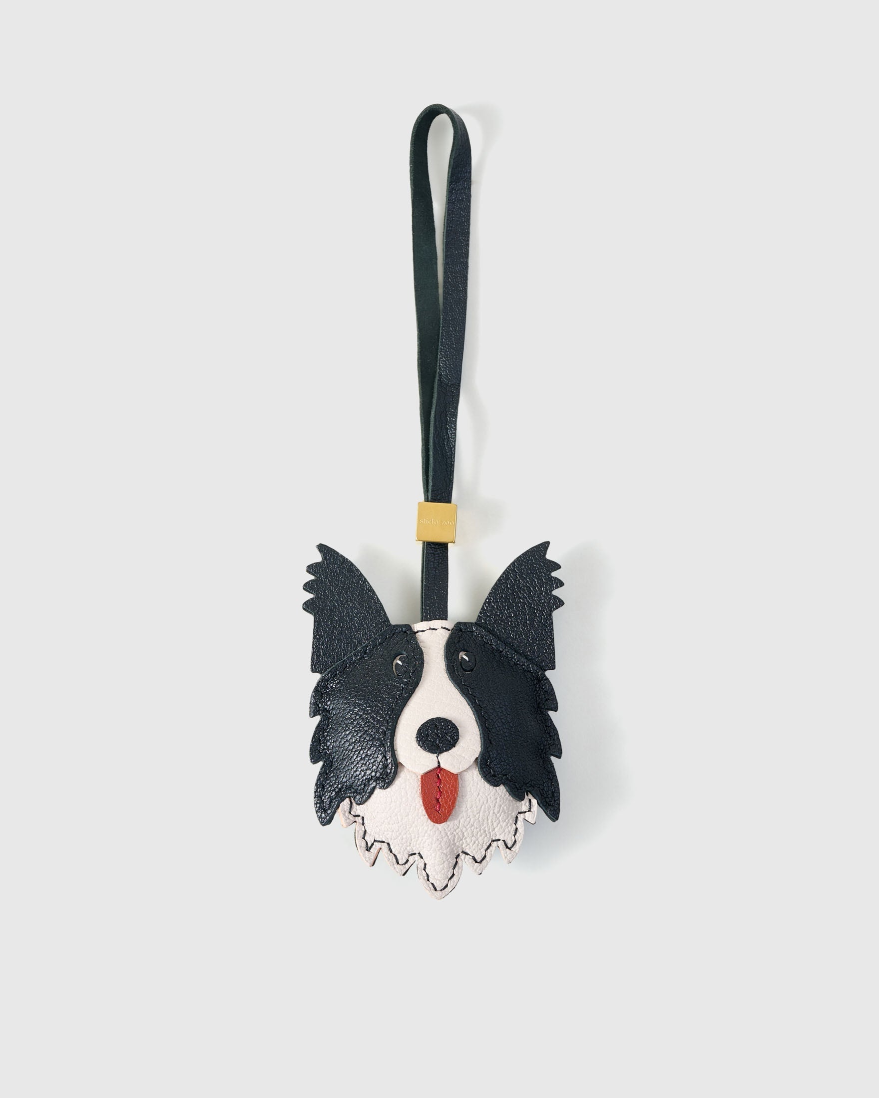 Border Collie charm handmade from French Alran genuine goatskin and French suede — real full-grain leather from Tarn, since 1903. 3 days of hand-cutting, hand-stitching, hand-layering. Arrives in luxury gift packaging. Designed in Amsterdam.
