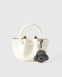 Close-up of handmade Poodle leather bag charm — hand-stitched visible edges on French Alran goatskin, 18K gold-plated cube hardware. STICKYZOO.