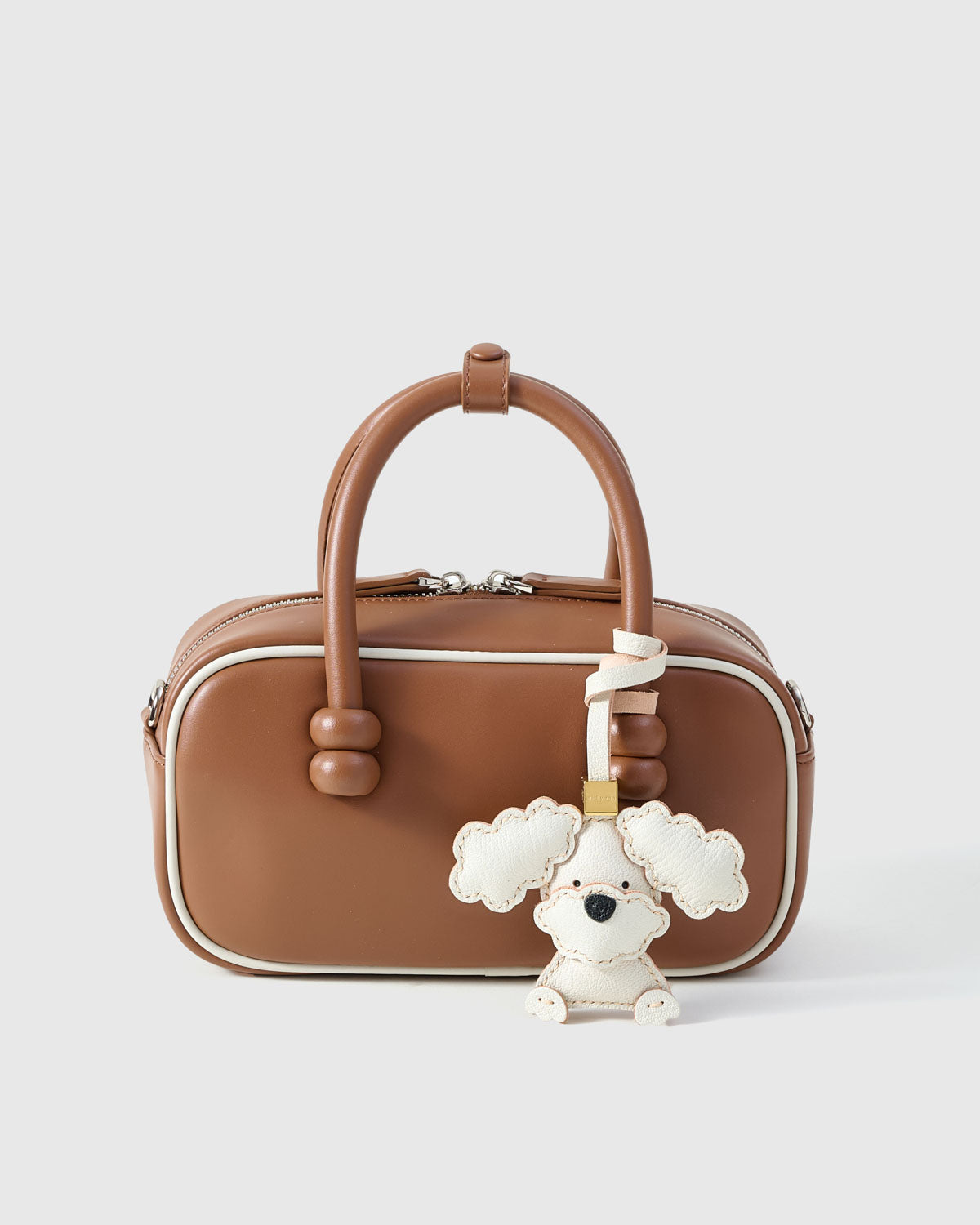 Poodle leather bag charm shown in both attachment options — handmade French Alran goatskin, dual attachment for bags or keys. STICKYZOO Amsterdam design.