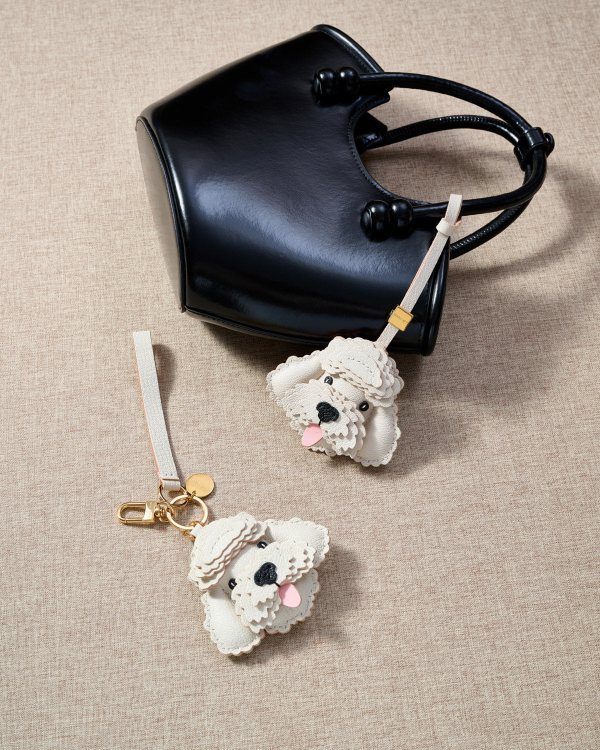 Close-up of handmade Poodle leather bag charm — hand-layered topknot curls in French Alran goatskin, hand-stitched edges. STICKYZOO Amsterdam design.